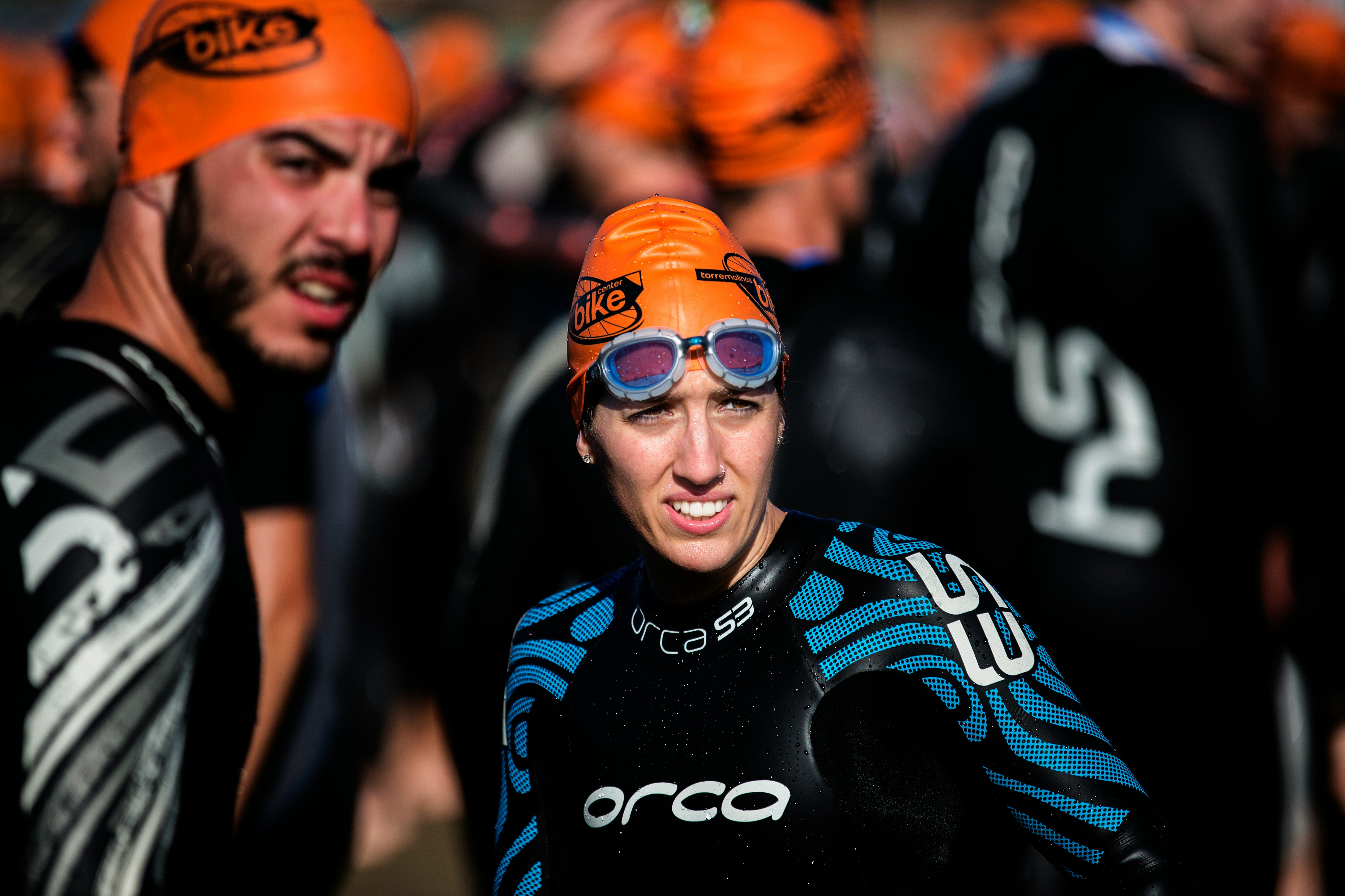 selective focus photography of woman wearing orange head cap and blue rashguard